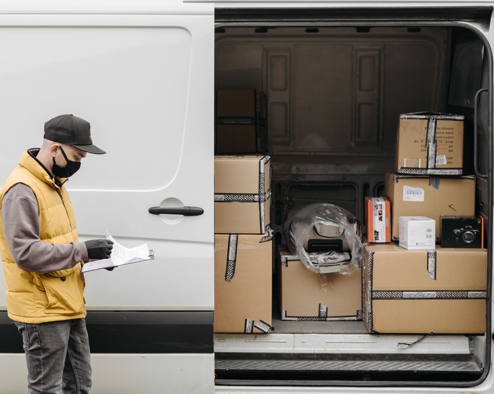 Man Wearing Face Mask Standing Near Vehicle Door with Brown Carton Boxes